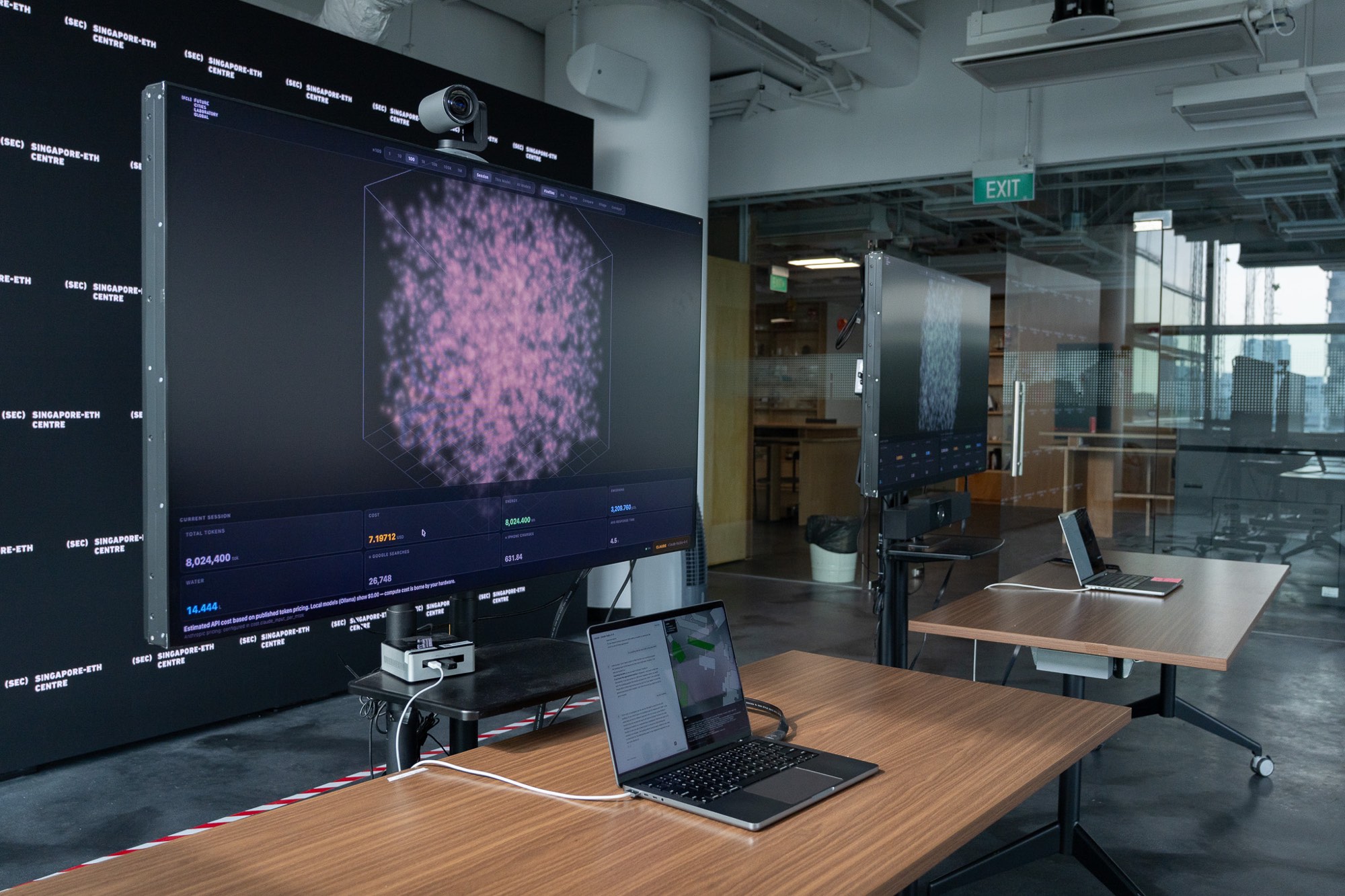 Exhibit station at Singapore-ETH Centre with the impact visualization display (left) showing real-time energy and productivity metrics, connected to a geospatial interface and AI chatbot control panel (right).